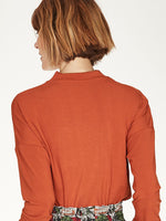 Spiced Orange top with twist neck slit detail and long cuffed sleeves.